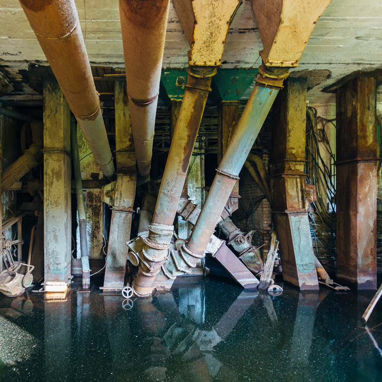 Flooded abandoned ruined factory. Old rusty pipes in dirty water