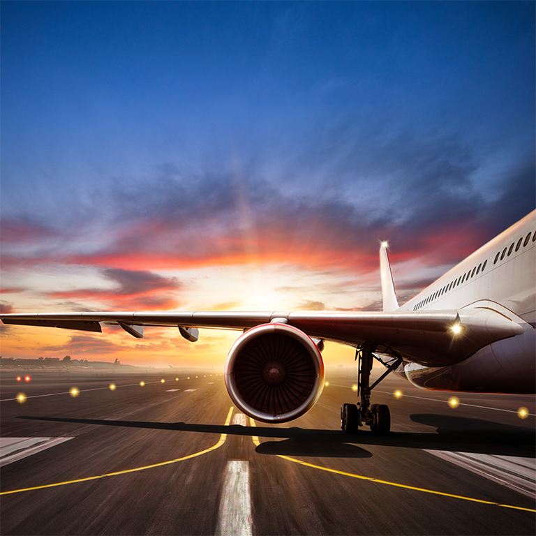 Close-up of passengers airplane on runway with silhouett of modern city, beautiful sunset light
