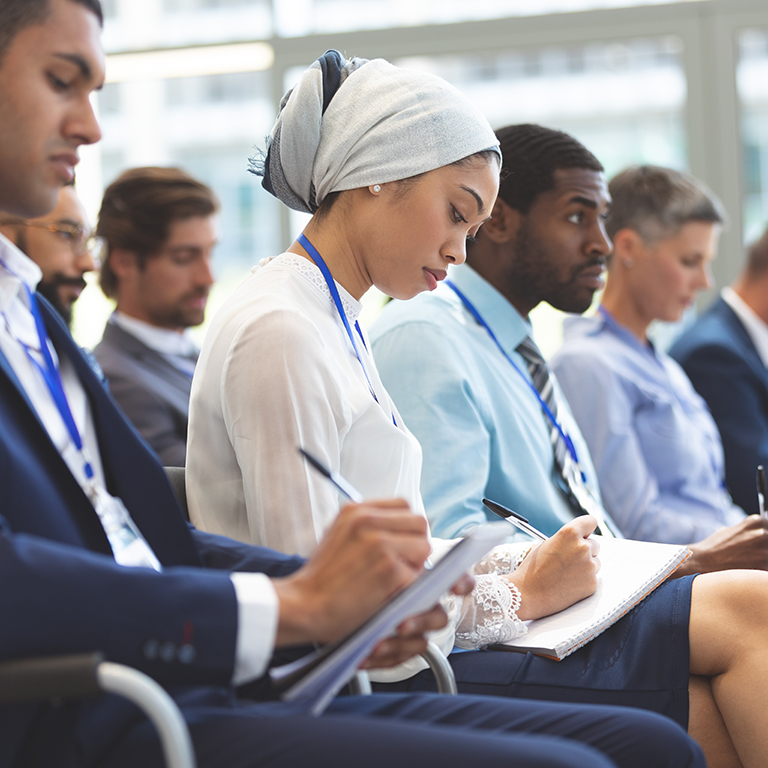 Business people writing on notepad during seminar