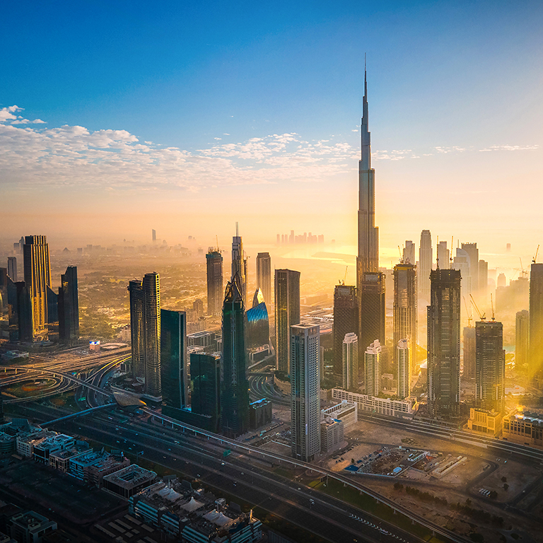 Aerial skyline of downtown Dubai filled with modern skyscrapers in the United Arab Emirates rising above the main city highway aerial view at sunrise