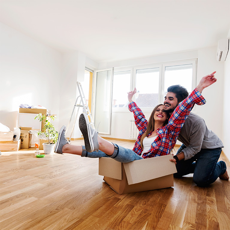 Happy young couple moving in new home unpacking boxes