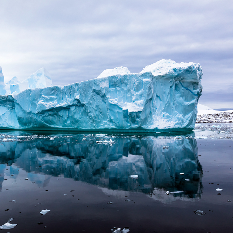 Impressive iceberg with blue ice and beautiful reflection on water in Antarctica, scenic landscape in Antarctic Peninsula. 