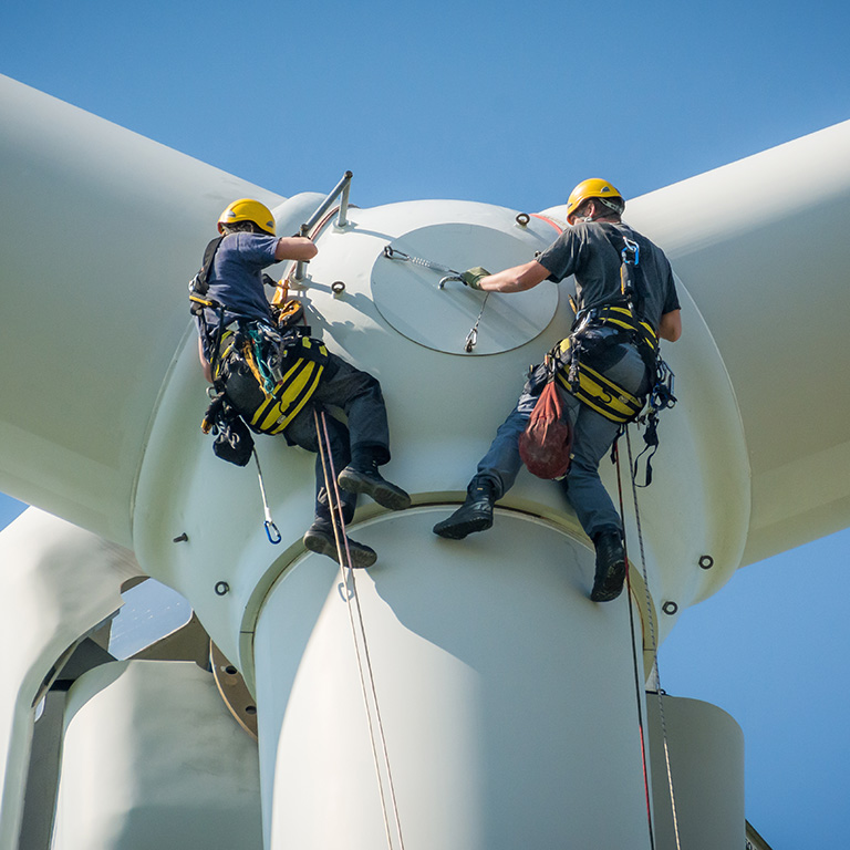 Inspection engineers preparing to rappel down a rotor blade of a wind turbine
