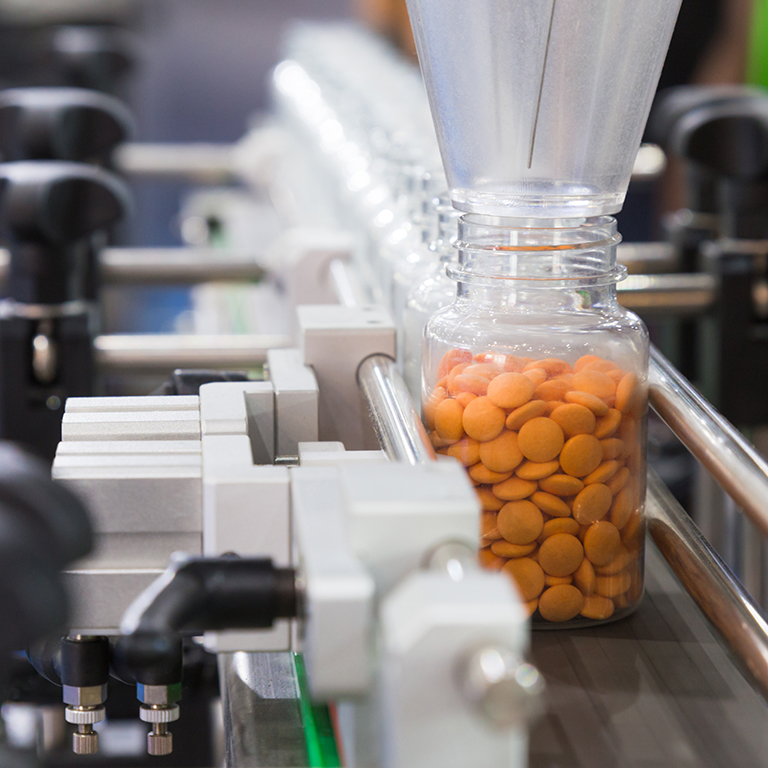 pharmaceutical industry, medicine pills are filling in the plastic bottle on production line machine conveyor at the medical factory. selective focus.