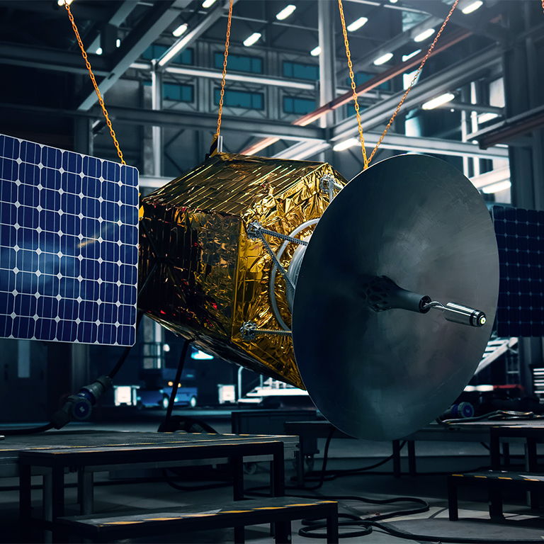 Satellite under construction in dark aerospace technology manufacturing facility. Development of spacecraft for space exploration,navigation, communications, internet telecommunication, observation.