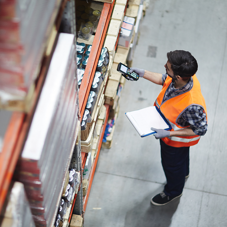 Worker with scanner checking inventory of goods in a warehouse.