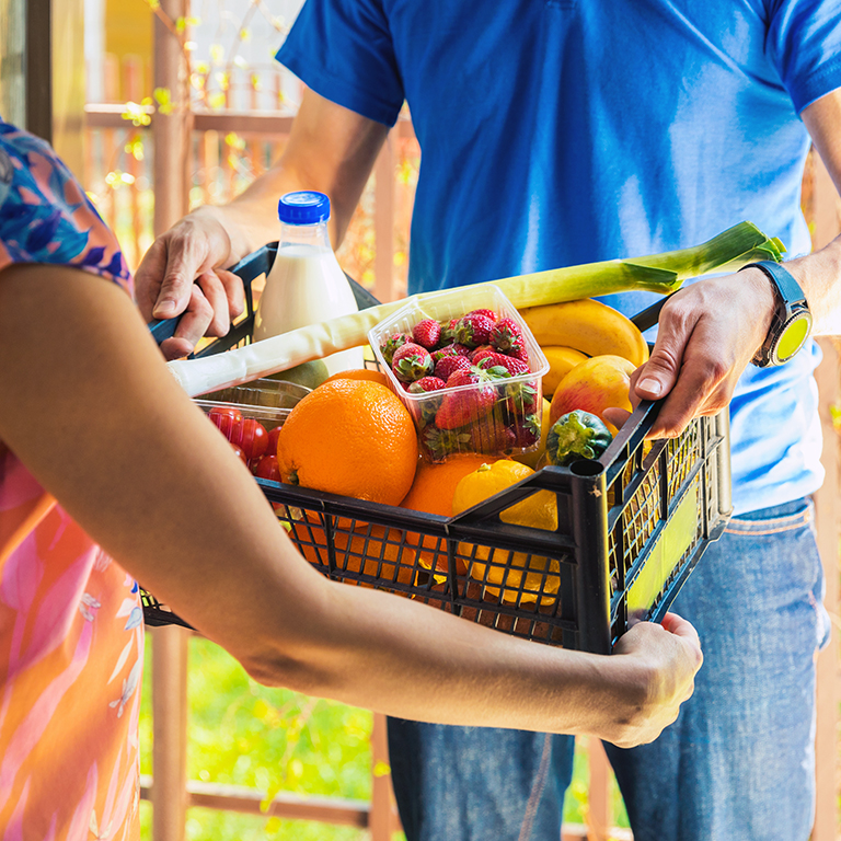 woman accepting groceries box from delivery man at home